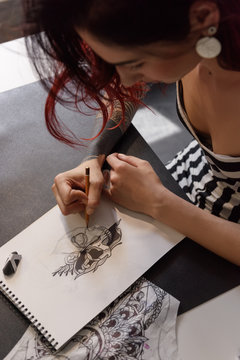 Girl drawing tattoo sketch in notebook