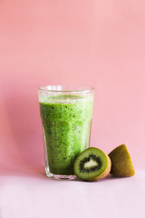 Healthy green smoothie with kiwi in a glass Cup on a pink background