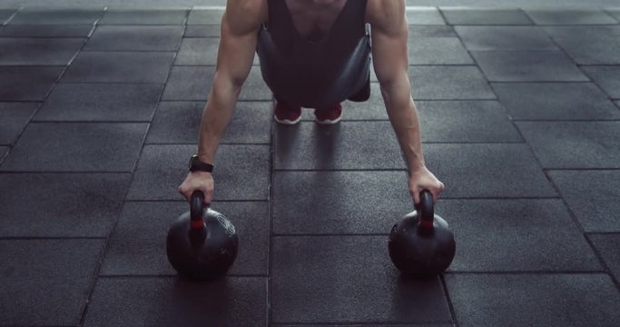 View straight athlete push-up on the weights in the gym