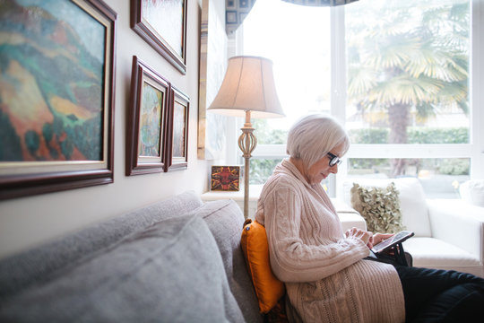 Senior woman using tablet at home on couch
