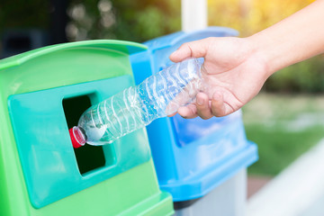 Fototapeta na wymiar Save the world concept, Hand throw plastic bottle into recycle bin