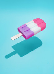 Pink popsicle ice cream with bright blue background and sun shadow. Summer food concept.
