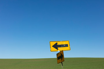 Bullet holes covering directional arrow signs, rural farmland in distance, Palouse, Washington