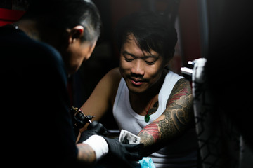 Professional asian tattooer makes a tattoo