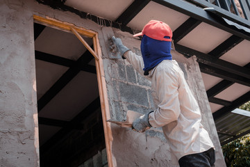 Construction workers plastering building wall using cement plaster