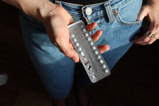 Young anonymous woman holding birth control pills