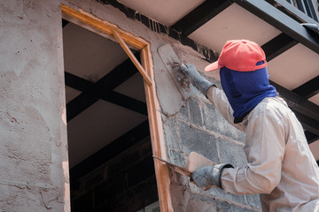Construction workers plastering building wall using cement plaster