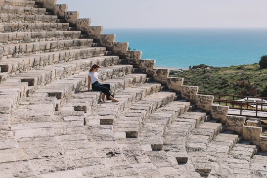 Stylish woman sitting on stairs of amphitheater