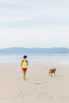 Unrecognizable woman with a dog walking on the beach