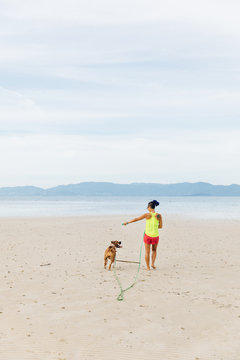 Sporty woman walking with a dog on the beach