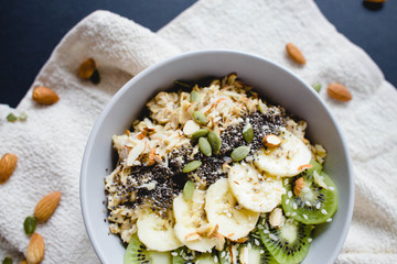 healthy breakfast of oatmeal with banana, kiwi on a white napkin and almond