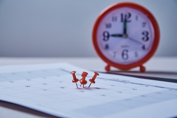 Time management, deadline and schedule concept: alarm clock and pushpin on schedule plan