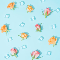 Pattern made of colorful flowers and ice cubes on pastel blue background. Minimal summer nature flat lay composition.