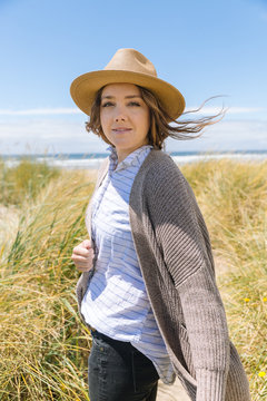 Portrait of woman with hat on beach in summer.