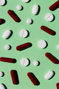 Scattered painkillers on a light green background