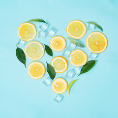 Creative summer background composition with lemon slices, straw and ice cubes. Minimal top down...