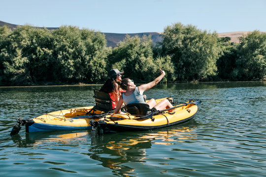 young women take selfie while kayaking on river