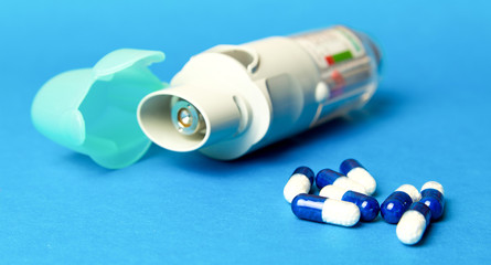  inhaler and pills against asthma on blue background. COPD