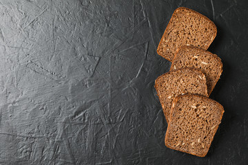 Rye bread pieces on black background, top view and space for text
