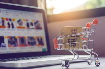 Shopping online concept - Parcel or Paper cartons with a shopping cart logo in a trolley on a...