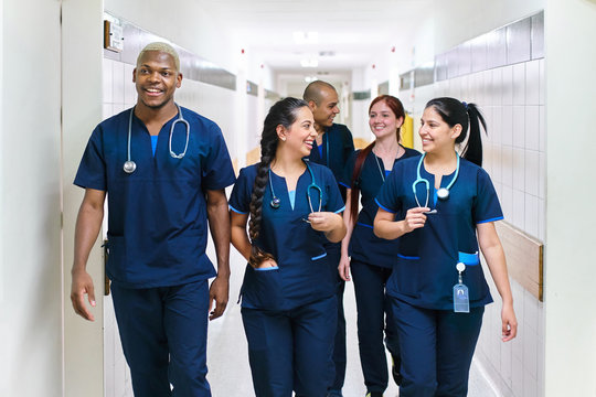 Smiling team of doctors walking in hospital corridor