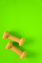 Fitness equipment with womens yellow weights/ dumbbells isolated on a lime green background with copyspace