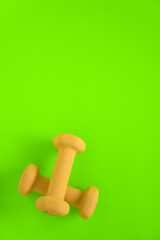 Fitness equipment with womens yellow weights/ dumbbells isolated on a lime green background with copyspace