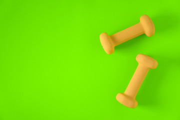 Fitness equipment with womens yellow weights/ dumbbells isolated on a lime green background with copyspace