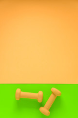Fitness equipment with womens yellow weights/ dumbbells isolated on a lime green and yellow background with copyspace