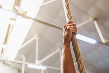 Crop hand gripping rope in gym