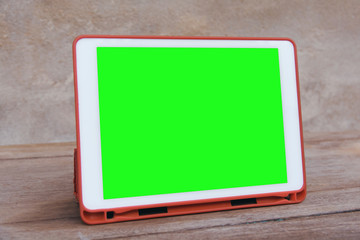 Mockup image of  White tablet pc with blank green desktop screen on wooden table.