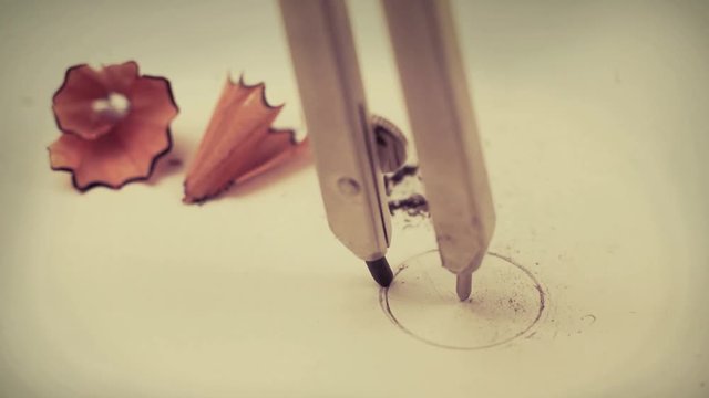 Closeup macro detail of drawing a circle with a precision geometry pencil compass on mathematics notebook paper with sharpening wood shavings with copyspace - Concept of school education, learning