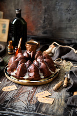 Delicious homemade chocolate bundt cake on wooden plate stands on rustic table