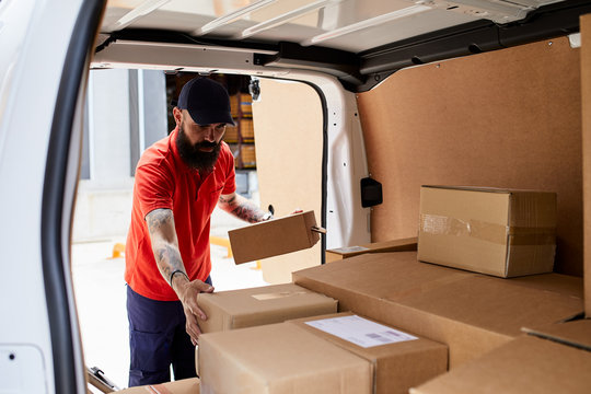 Worker in cap loading the truck with packages.