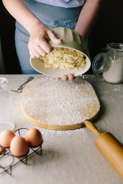 Woman tipping out bowl of dough for scones onto floured board