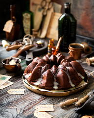 Delicious homemade chocolate bundt cake on wooden plate stands on rustic table