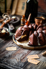 Delicious homemade chocolate bundt cake on wooden plate stands on rustic table