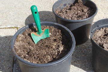 Plastic flowerpot with loam and gardening trowel