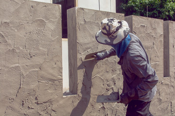 Construction workers plastering building wall using cement plaster