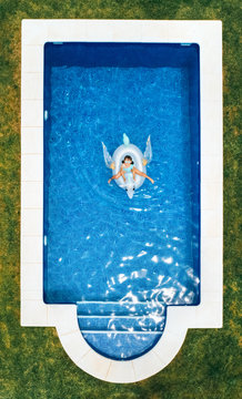 Little girl on a unicorn shaped float in a swimming pool