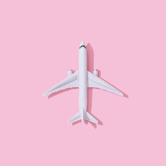 Creative composition made with passenger plane on pastel pink background. Summer travel or vacation concept.