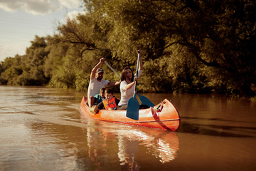 Family paddling red canoe in the river.