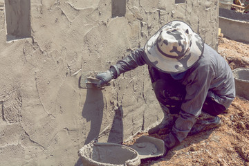 Construction workers plastering building wall using cement plaster