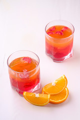 Jelly dessert with strawberries in drink glass with orange slices nearby