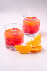 Jelly dessert with strawberries in drink glass with orange slices nearby
