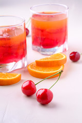 Jelly dessert with strawberries in drink glass with cherry berries and orange slices nearby
