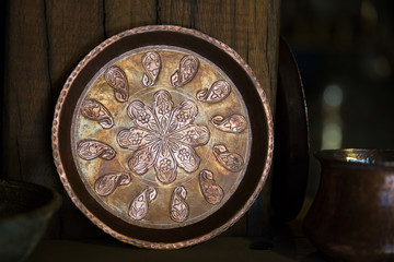 Fototapeta na wymiar Copper plate handcrafted, traditionally made in Lagich, Azerbaijan. Handmade plate in souvenir shop.