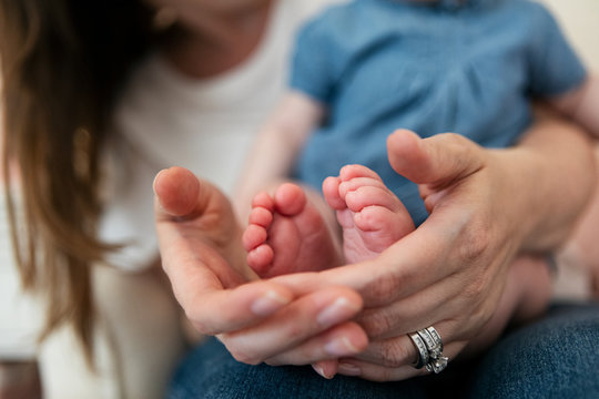 Family: Mother Holds Baby Girl's Feet In Hands