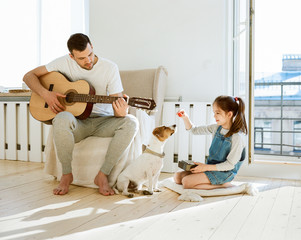 Girl playing dog near father with guitar