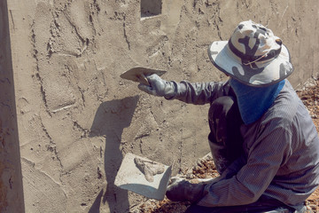 Construction workers plastering building wall using cement plaster